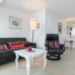 Wohnzimmer mit Sofa, Sessel und Esstisch im Hintergrund.
