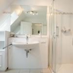 Badezimmer mit Dusche, Waschbecken und Spiegel unter Dachschräge