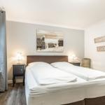 Bedroom with double bed, window, and wall art. Two nightstands with lamps.