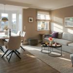Living and dining area with sofa, table and chairs. Large windows and light walls.