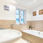 Bathroom with bathtub, sink, and window with sea view.