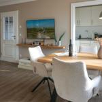 Dining area with wooden table, chairs, and TV mounted on the wall.