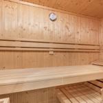 Sauna with wooden benches and temperature gauge on the wall.