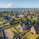 Aerial view of a coastal village with houses and the sea in the background.