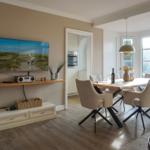 Living and dining area with TV, dining table, and windows