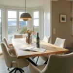 Dining room with wooden table, chairs, and window view.