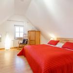 Schlafzimmer mit rotem Bett, Holzboden und Dachschrägen