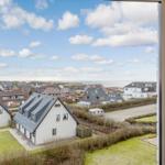 Aus dem Fenster sieht man Häuser und das Meer unter einem blauen Himmel mit weißen Wolken.