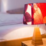 Tischlampe mit farbigem Schirm auf Nachttisch neben Bett
