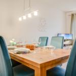 Esszimmer mit Holztisch, blauen Stühlen und Wanddekoration SEA SIDE.