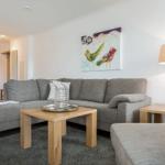 Living room with gray sofa, wooden table, and wall art with birds.
