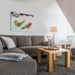 A living room with a gray sofa, wooden table, and wall art with birds.