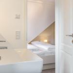 Bathroom with sink and view into bedroom with bed and lamp.