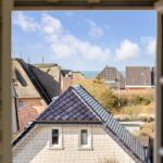 Through the window you see roofs and the sea.