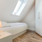 Bedroom with sloped ceiling, bed, nightstand, and wardrobe.
