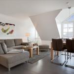 Living and dining area with sofa, table and chairs. Large windows and wall art with birds.