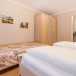 Two beds, wardrobe, and pictures on the wall.
