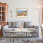 Living room with gray sofa, two chairs, and glass table.