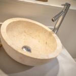 Stone basin with modern faucet on a simple countertop.
