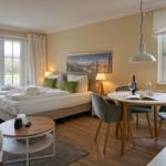 Bedroom with bed, dining table, and view of green field.