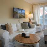 Living area with sofa, TV, and sleeping area. French doors lead outside.