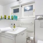 Badezimmer mit Waschbecken, Spiegel, Toilette und Heizkörper.