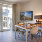 Esszimmer mit Tisch, Stühlen und TV. Durchgang zur Terrasse mit Gartenmöbeln.