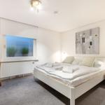 Schlafzimmer mit Bett, Fenster und Sessel.