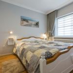 Schlafzimmer mit Bett, Wandbild und Fenster mit Jalousie.