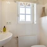 Badezimmer mit Waschbecken, Spiegel und Fenster