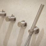 Duschkopf und Bedienelemente an Wand mit Steinfliesen