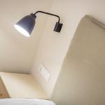 Schlafzimmer mit Nachttisch und Wandlampe.