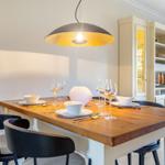 Holztisch mit Stühlen, Deckenleuchte und Sideboard im Essbereich.