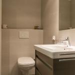 Badezimmer mit Waschbecken, Spiegel, Toilette und Handtuchhalter.