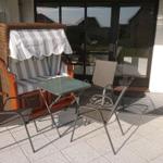 Terrasse mit Liege, Tisch und Stühlen vor Glasfront