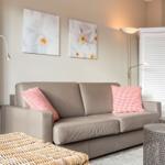 Gray sofa with checkered cushions, wall art, and white louvered cabinet.