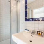 Bathroom with shower, sink, and mirror with blue frame.