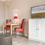 Dining area with table, two chairs, and TV on white cabinet