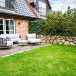 Terrace with seating area and garden. House with stone wall and green hedge.