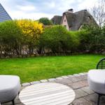 Terrace with seating and view of a lawn and hedges.