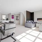 Modern living and dining area with sofa, dining table, and fireplace.