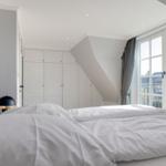 Bedroom with double bed, white wardrobes, and window with view.