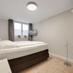 Bedroom with bed, window, wardrobe, and TV.