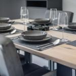 Dining room with wooden table, gray chairs, and tableware.