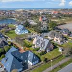 Aerial view of houses with green areas and sea view.