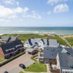 Holiday homes near the beach with sea view and green dunes.