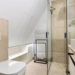 Badezimmer mit Dusche, Waschbecken und Toilette unter Dachschrägen.