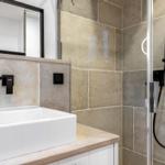 Badezimmer mit Waschbecken, Spiegel und Dusche mit Duschbrause