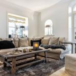 Wohnzimmer mit Sofa, Couchtisch und Fenstern.