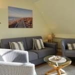 Living room with sofa, armchairs, and glass table under sloped ceiling
